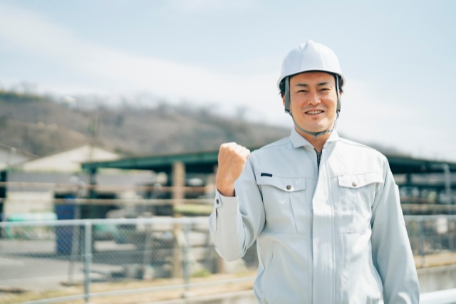 ガッツポーズをする作業着の男性